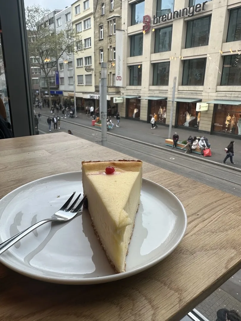 Stück Cheesecake am Fenster mit Blick auf die Kaiserstraße und Breuninger